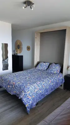a bedroom with a bed with a blue and white comforter at Studio AJACCIO Sanguinaires in Ajaccio