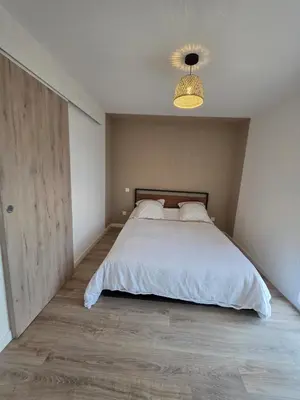 a bedroom with a large bed and a chandelier at T2 proche de la mer in Venzolasca