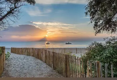 a fence on a beach with boats in the water at T2 proche de la mer in Venzolasca