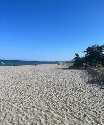 a sandy beach with people sitting on the beach at T2 proche de la mer in Venzolasca