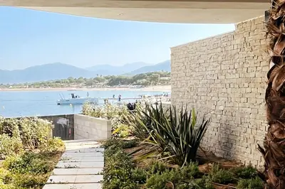 a brick wall next to a beach with a boat in the water at Rare T2 New, Waterfront in Porticcio