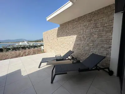a table and bench on a patio with a brick wall at Rare T2 New, Waterfront in Porticcio