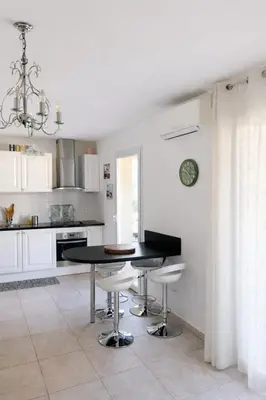 a kitchen with a black table and white cabinets at Appart cosy - Lumineux avec terrasse in Borgo