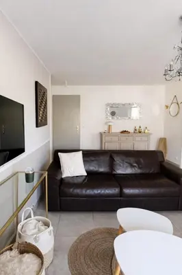 a living room with a black leather couch at Appart cosy - Lumineux avec terrasse in Borgo