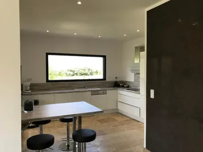 a kitchen with a table and stools and a window at Villa proche de St Florent Corse in Oletta