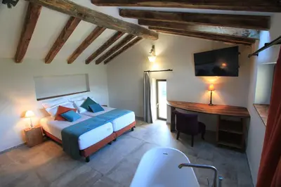 a bedroom with a bed and a desk and a tub at Casa Una Storia in Sartène