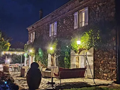 a stone house with a bench outside at night at Holiday Home Exklusivität Korsika- Steinhaus mit Charme by Interhome in Santa-Lucia-di-Moriani