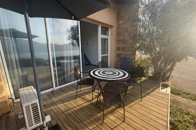 a table and chairs on a deck with an umbrella at Appartement Duplex 6 personnes - Soléa 204 - Vue Mer in Serra-di-Ferro