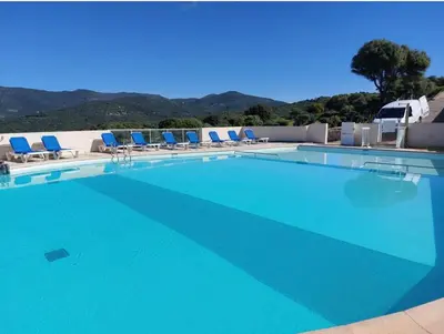 a large swimming pool with blue chairs and mountains at Appartement Duplex 6 personnes - Soléa 204 - Vue Mer in Serra-di-Ferro
