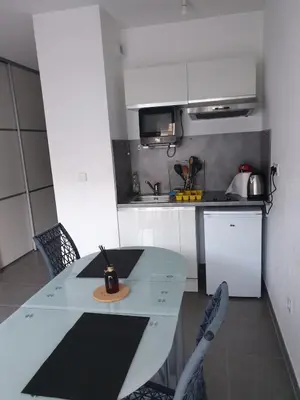 a white kitchen with a table and chairs at Studio récent Corte in Corte