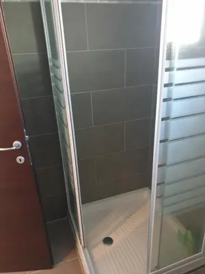 a shower stall with a glass door with a drain at Studio récent Corte in Corte