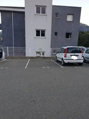 a white van parked in a parking lot in front of a building at Studio récent Corte in Corte
