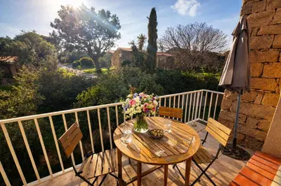 a wooden table with flowers on a balcony with an umbrella at Appartement 4 personnes - Soléa 126 - Vue Nature in Serra-di-Ferro
