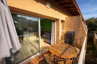 a balcony with a table and a patio with a glass door at Appartement 4 personnes - Soléa 126 - Vue Nature in Serra-di-Ferro