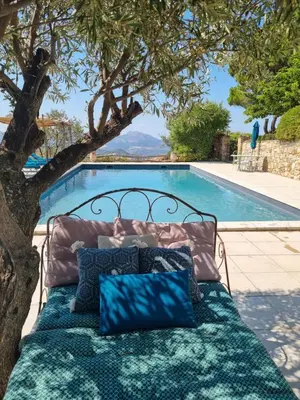 a bed sitting under a tree next to a swimming pool at Ferme Canioni in Belgodère