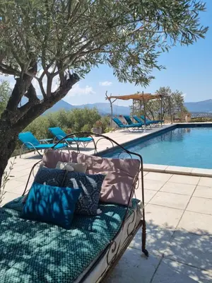 a bench with pillows sitting next to a swimming pool at Ferme Canioni in Belgodère