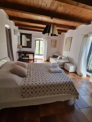 a bedroom with a large bed and a living room at Ferme Canioni in Belgodère