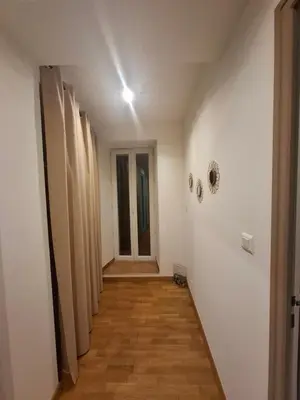 a hallway with white walls and wooden floors and a door at Appartement terrasse au cœur d'Ajaccio in Ajaccio