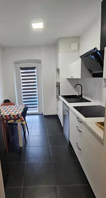 a kitchen with white cabinets and a table and a sink at Séjournez entre mer et montagne en Corse-du- Sud in Cauro