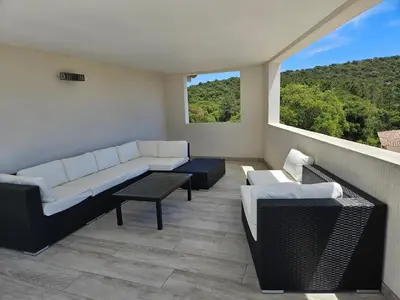 a balcony with a couch and chairs and a window at Villa Luxueuse avec piscine privee chauffee in Porto-Vecchio