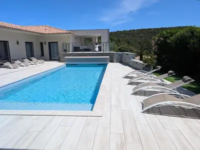 a swimming pool with lounge chairs next to a house at Villa Luxueuse avec piscine privee chauffee in Porto-Vecchio