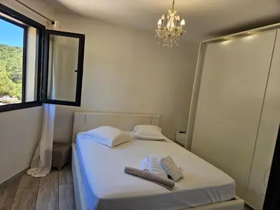 a bedroom with a bed with a chandelier and a window at Villa Luxueuse avec piscine privee chauffee in Porto-Vecchio