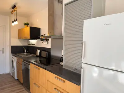 a kitchen with a white refrigerator and wooden cabinets at Bel appartement F2 dans résidence calme in Casaglione