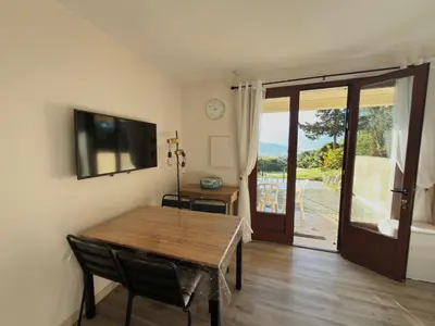 a dining room with a table and a sliding glass door at Bel appartement F2 dans résidence calme in Casaglione