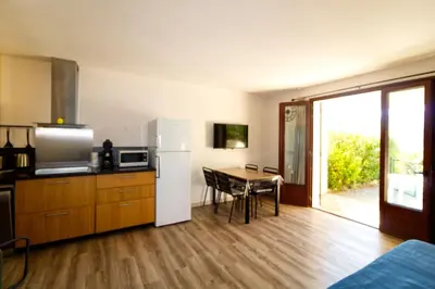 a kitchen with a refrigerator and a table with chairs at Bel appartement F2 dans résidence calme in Casaglione