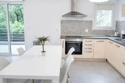 a white kitchen with a white table and chairs at Grand F2 avec terrasse spacieuse, Centre Corte in Corte