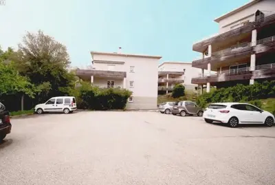 a parking lot with cars parked in front of a building at Grand F2 avec terrasse spacieuse, Centre Corte in Corte