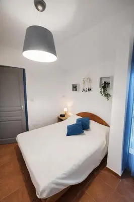 a bedroom with a large white bed with blue pillows at Mini-villa 4 personnes - Soléa 20 - vue mer in Serra-di-Ferro