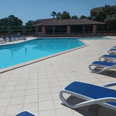 a swimming pool with blue lounge chairs in a resort at CORSE Bravone bel appart à 2 pas de la plage 2ch et mezzanine in Linguizzetta