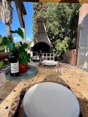 a table with a white plate and a bottle of wine at Luce di Mare Studio - Near Santa-Giulia in Porto-Vecchio