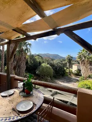 a table on a balcony with a view of the mountains at Luce di Mare Studio - Near Santa-Giulia in Porto-Vecchio