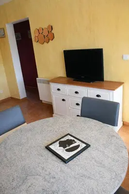 a room with a table with chairs and a television at Mini-villa 4 personnes - Soléa 19 - vue mer in Serra-di-Ferro