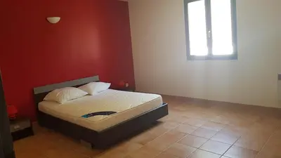 a bedroom with a bed with a red wall and a window at domaine d alistro avec grande piscine in Canale-di-Verde