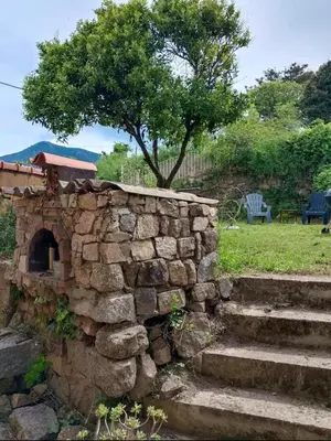 a stone wall with stairs and a tree at Maison typique village corse in Sari-dʼOrcino