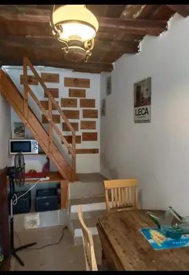 a dining room with a wooden table and a staircase at Maison typique village corse in Sari-dʼOrcino