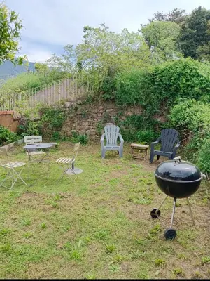 a grill in a yard with chairs and a table at Maison typique village corse in Sari-dʼOrcino