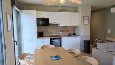 a kitchen with white cabinets and a table and chairs at T3 Casa di Giulia neuf grande terrasse - Lumineux - Plage à 5 min in Zonza