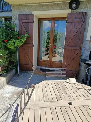 a porch with a wooden door and a chair at Authentique maison de hameau in Altagene
