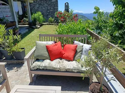 a bench with three pillows on it with plants at Authentique maison de hameau in Altagene