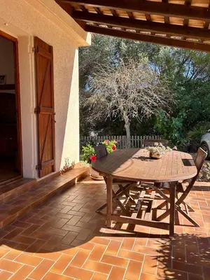 a wooden table and chairs on a patio at Appartement calme jardin vue mer sur les hauteurs in Grosseto-Prugna