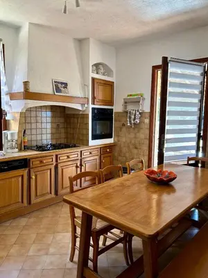 a kitchen with a wooden table and a dining room at Appartement calme jardin vue mer sur les hauteurs in Grosseto-Prugna