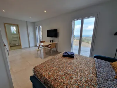 a bedroom with a bed and a table and a television at Studio neuf , vue mer et montagne in Lavatoggio