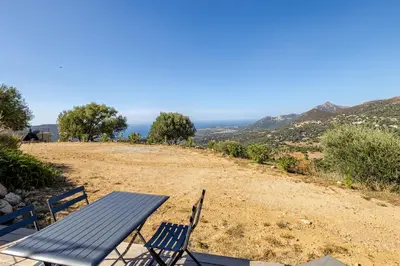a picnic table and chairs sitting on top of a hill at Studio neuf , vue mer et montagne in Lavatoggio