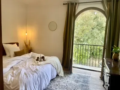 a bedroom with a bed and a large window at Un étage entier - 5 chambres indépendantes et 3 salles de bains in Corte