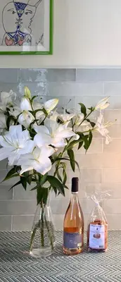 a vase with white flowers and a bottle of alcohol at Elegant 2-bedroom terrace in the heart of the city in Ajaccio
