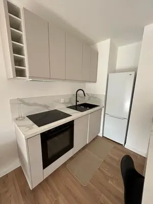 a kitchen with white cabinets and a sink and a refrigerator at T2 Cosy Centre Ajaccio in Ajaccio